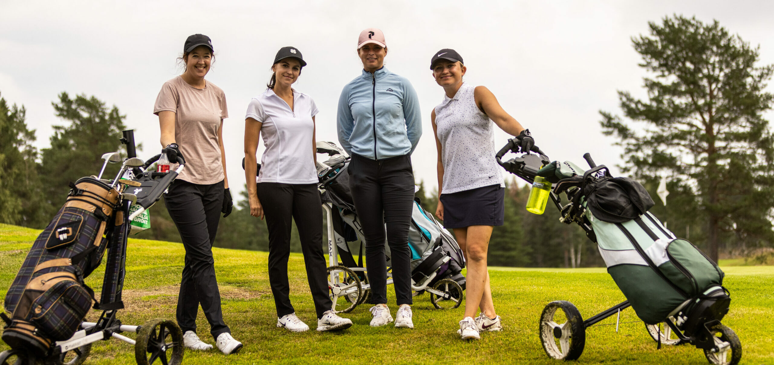 Golfbilar står parkerade på rad utanför klubbhuset.